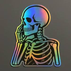 Holographic vinyl sticker featuring a side-profile skeleton in a thoughtful pose, resting its cheek on one hand. The design is enhanced with a rainbow sheen that shifts with light, creating a visually striking and reflective effect. Printed on clear vinyl with smooth contour edges. Designed by PuffSticker.com for gothic-themed sticker sets, anatomy-inspired art, and alternative stationery collections.