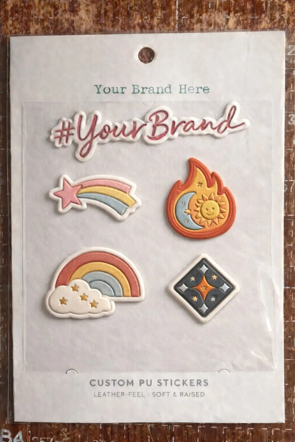 A vertical display sheet of custom PU stickers featuring a colorful rainbow, star, and sun-moon flame design. Each sticker shows a soft, raised convex effect and a matte, leather-like grain texture.