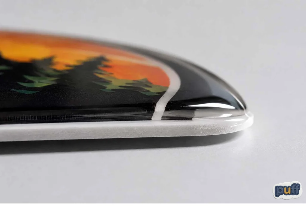 Macro close-up of a puffy sticker's domed edge showing the raised clear coating over the printed design