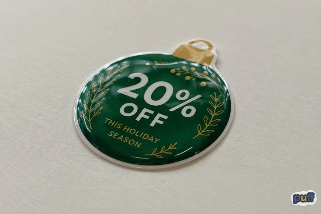 Close-up of a custom green 20% off holiday puffy sticker showing its raised glossy surface and dimensional finish.